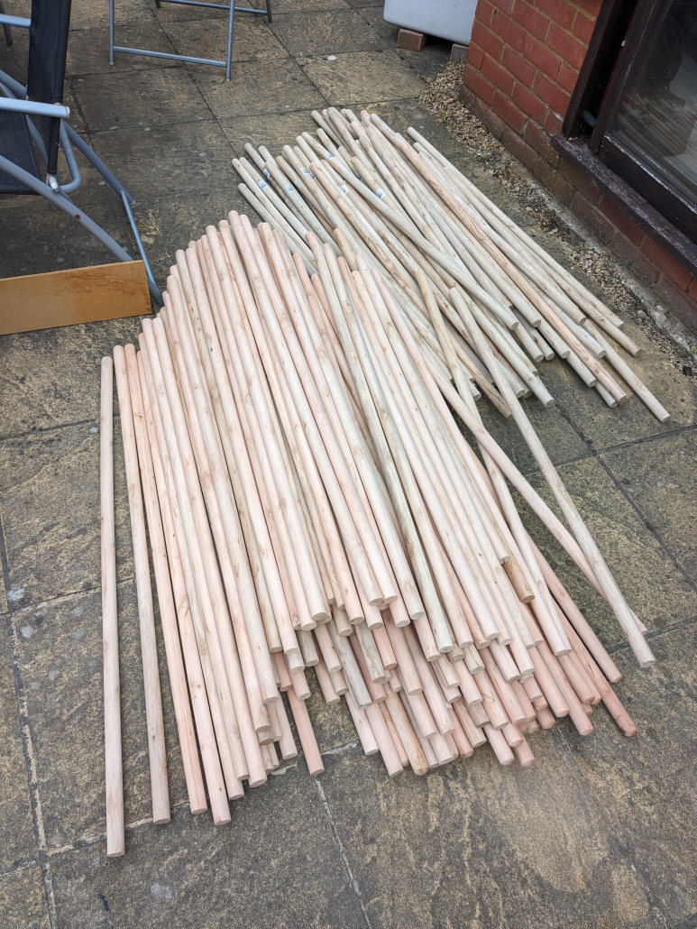 A pile of broom handles laying on the floor